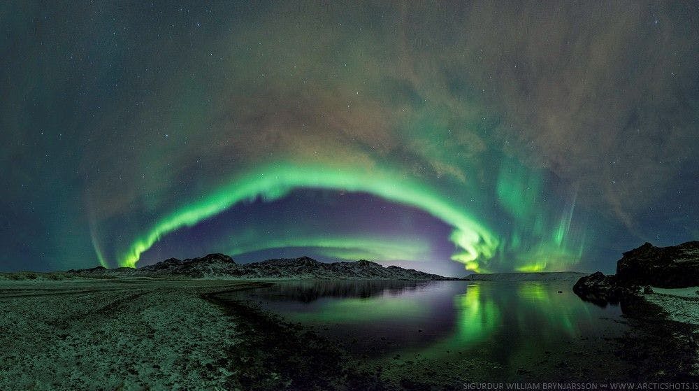 A panorama of the Northern lights reflecting in the lake at Kleifarvatn